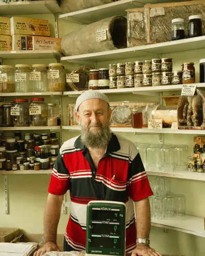 Imker in zijn winkel tussen schappen vol potten honing